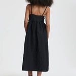 Back view of black ambra dress on model wearing black sneakers, against a white background.