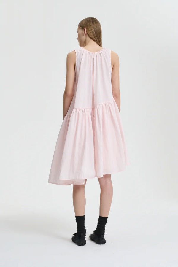 Back view of blush pink azelia dress on model wearing black sneakers and socks, against a white background.