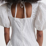 Back closeup view of white bali dress on model, against a white background.