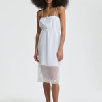 Front view of white barr dress on model wearing black flats, against a white background.