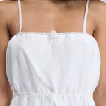 Front closeup view of white barr dress on model, against a white background.