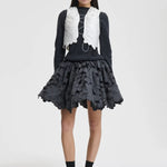 Front view of snow white breno vest on model wearing black dress and sneakers, against a white background.