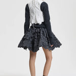 Back view of snow white breno vest on model wearing black dress and sneakers, against a white background.