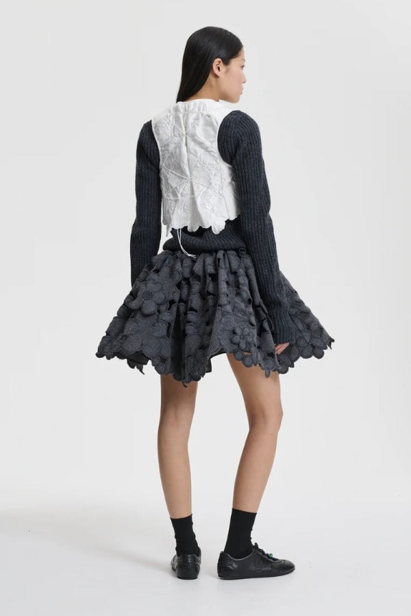 Back view of snow white breno vest on model wearing black dress and sneakers, against a white background.