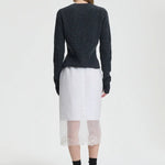 Back view of white bria skirt on model wearing grey sweater and black sneakers, against a white background.