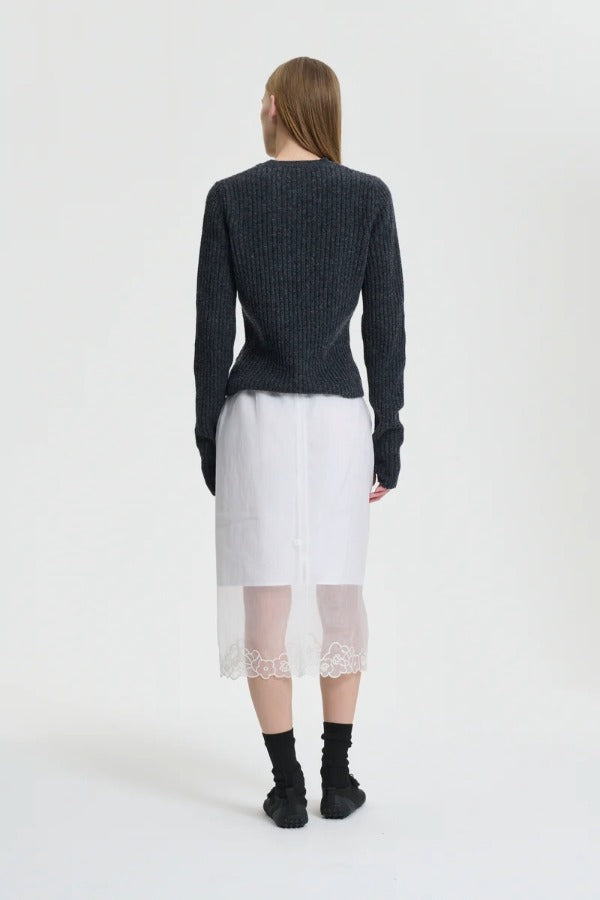 Back view of white bria skirt on model wearing grey sweater and black sneakers, against a white background.