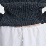 Front top closeup view of bria skirt on model wearing grey sweater, against a white background.