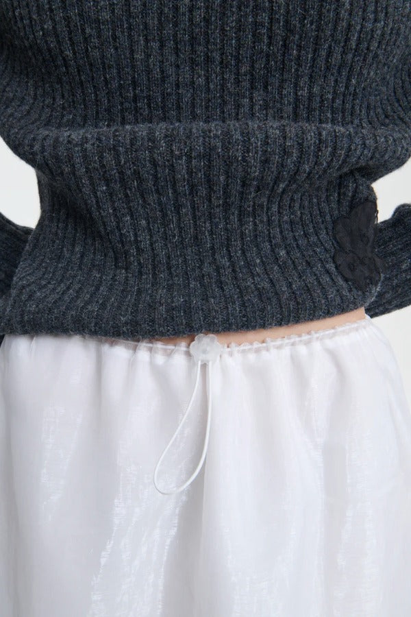 Front top closeup view of bria skirt on model wearing grey sweater, against a white background.