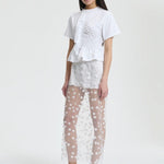 Front view of white gus skirt on model wearing whiter shorts and top with flats, against a white background.