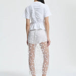 Back view of gus skirt on model wearing white shorts and top with flats, against a white background.
