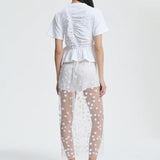 Back view of gus skirt on model wearing white shorts and top with flats, against a white background.