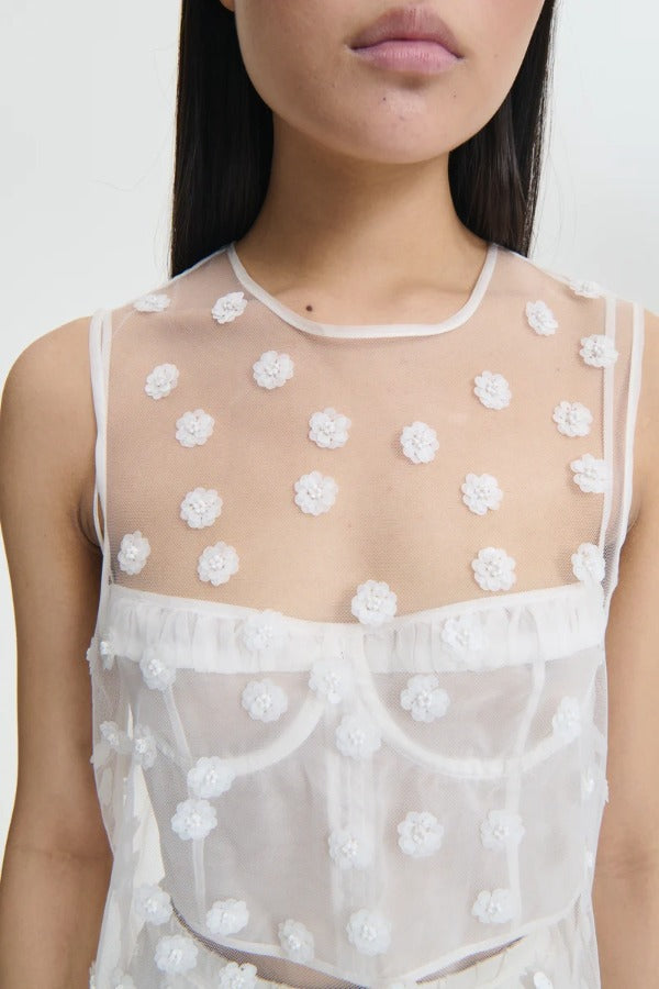 Front closeup view of white utania top on model wearing white brassiere against a white background.