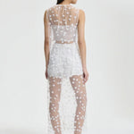 Back view of white utania top on model wearing white shorts and black flats, against a white background.