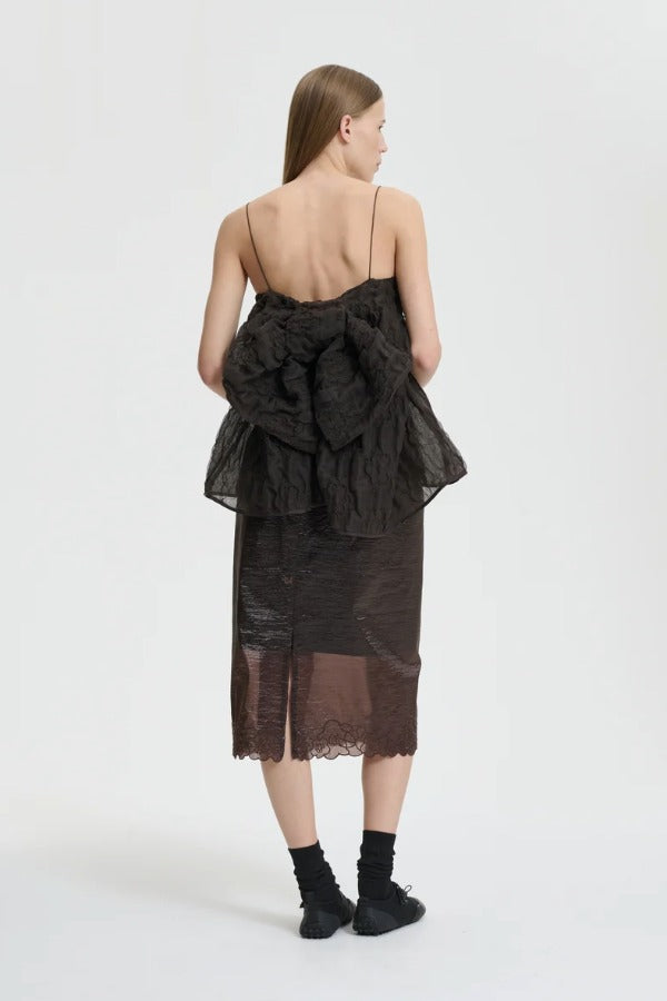 Back view of soil brown veronica top on model wearing brown skirt and sneakers with socks, against a white background.