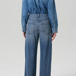 Back view of boardwalk jeans in jete on model wearing jean short and black heels, against a white background.