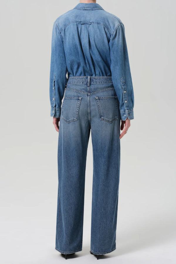 Back view of boardwalk jeans in jete on model wearing jean short and black heels, against a white background.