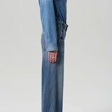 Side view of boardwalk trouser in jete on model wearing jean shirt and black heels against a white background.