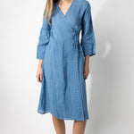 Front view of denim wrap dress on barefoot model, against a white background.