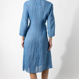 Back view of denim wrap dress on barefoot model, against a white background.