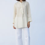 Front view of kora little subhash shirt on model wearing white pants and natural sandals, against a white background.