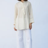 Front view of kora little subhash shirt on model wearing white pants and natural sandals, against a white background.