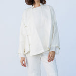 Front closeup view of rice mandarin jacket on model wearing rice pants, against a white background.