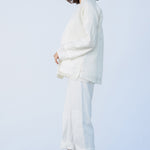 Side view of rice mandarin jacket on model wearing rice pants and natural sandals, against a white background.