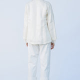 Back view of rice mandarin jacket on model wearing rice pants and natural sandals, against a white background.
