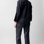 Back view of midnight mandarin jacket on model wearing midnight pants and natural sandals, against a white background.
