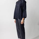 Side view of midnight mandarin jacket on model wearing midnight pants and natural sandals, against a white background.