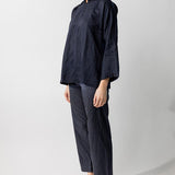 Side view of midnight mandarin jacket on model wearing midnight pants and natural sandals, against a white background.