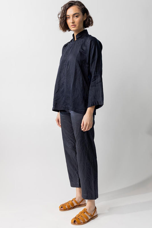 Side view of midnight mandarin jacket on model wearing midnight pants and natural sandals, against a white background.
