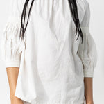 Front closeup view of rice mary ellen mark blouse on model wearing rice pants, against a white background.