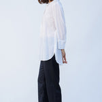 Side view of midnight pajama pant on model wearing white tunic and natural sandals, against a white background.