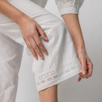 Bottom Hem closeup of rice pants with lace on model wearing rice top, against a white background.