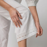Bottom Hem closeup of rice pants with lace on model wearing rice top, against a white background.