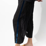 Side closeup view of ribbon detail of pants on model wearing midnight top and natural sandals, against a white background.