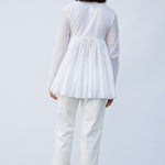 Back view of rice rabari jacket on model wearing white pants and natural sandals, against a white background.