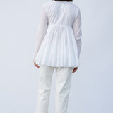 Back view of rice rabari jacket on model wearing white pants and natural sandals, against a white background.