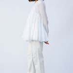 Side view of rice rabari jacket on model wearing white pants and natural sandals, against a white background.