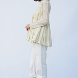 Side view of kora rabari jacket on model wearing white pants and natural sandals, against a white background.