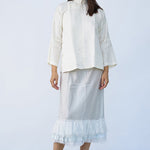 Front view of tint ruffle skirt on model wearing mandarin jacket and natural sandals, against white background.