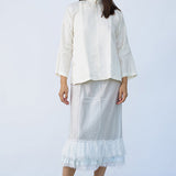Front view of tint ruffle skirt on model wearing mandarin jacket and natural sandals, against white background.