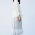 Side view of tint ruffle skirt on model wearing mandarin jacket and natural sandals, against a white background.