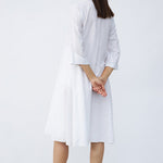 Back view of rice short tule dress on model wearing natural sandals, against a white background.
