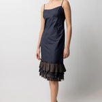 Front slanted view of midnight slip with ruffles on model wearing natural sandals, against a white background