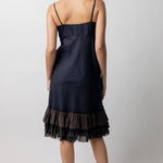 Back view of midnight slip with ruffles on model wearing natural sandals, against a white background.
