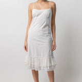 Front view of rice slip with ruffles on model wearing natural sandals, against a white background.