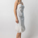 Side view of rice slip with ruffles on model wearing natural sandals, against a white background.