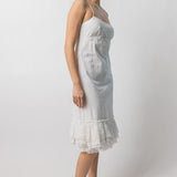 Side view of rice slip with ruffles on model wearing natural sandals, against a white background.